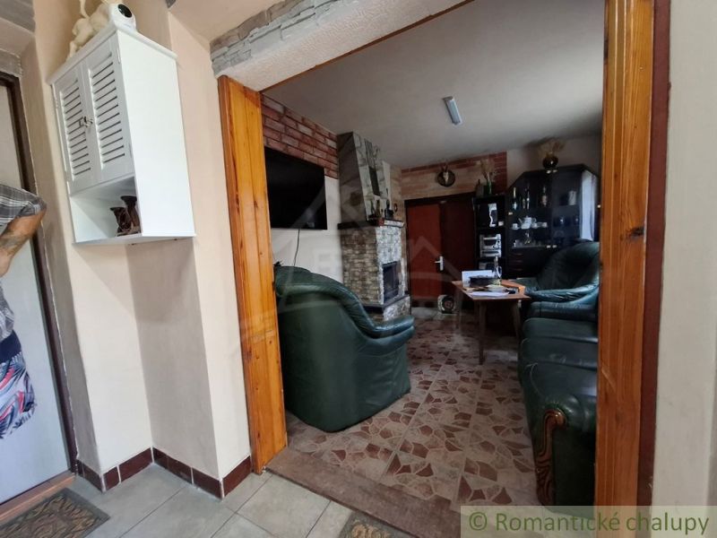 Wohnzimmer in einer Hütte mit Kamin, Ledersitzgruppe und weißem Schrank.