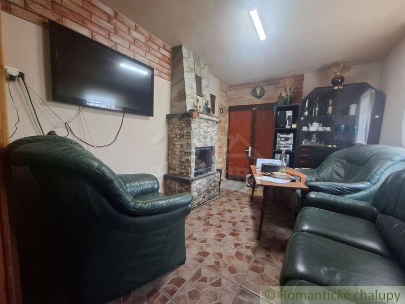 Ein Kamin aus Stein und Ledersofas in einer Hütte mit einem Boden im Fliesenstil.