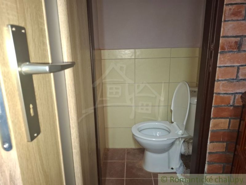 Eine Toilette mit Fliesen und einer Ziegelwand im Inneren einer Hütte.