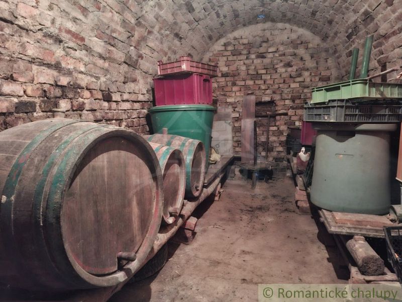 Ein steinerner Keller in der Hütte mit Holzfässern und Plastikbehältern.