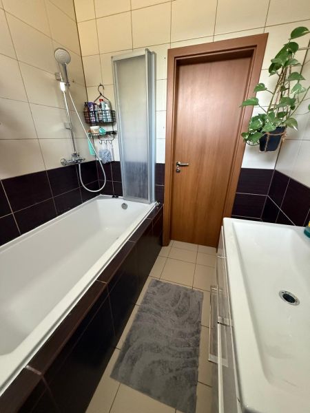 Badezimmer in einer 3-Zimmer-Wohnung mit Badewanne, Waschbecken und Fliesen, geeignet für Komfort.