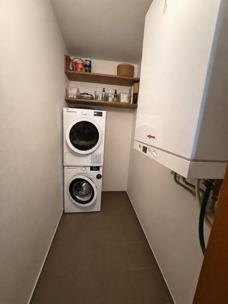 Waschküche in einer 3-Zimmer-Wohnung mit Waschmaschine, Trockner, Regalen und Gastherme.