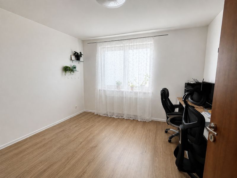 Ein Zimmer in einer 3-Zimmer-Wohnung mit einem Holzboden und einem Schreibtisch.