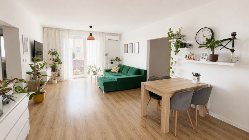 Wohnzimmer mit Holzboden, grünem Sofa und Pflanzen in einer 3-Zimmer-Wohnung.