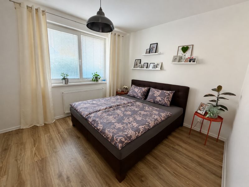 Schlafzimmer mit Bett, Holzboden und Dekorationen in einer 3-Zimmer-Wohnung.