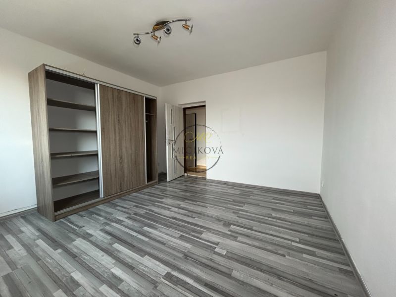 Geräumiges Zimmer mit Holzboden und Einbauschrank in einer 2-Zimmer-Wohnung.