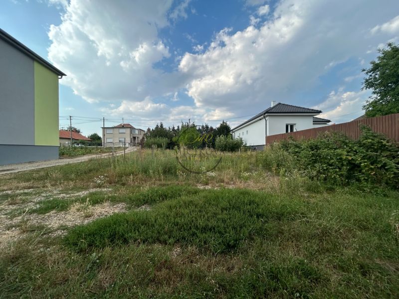Ein Garten in der Umgebung von Häusern in Telince mit wechselnder Bewölkung am Himmel.