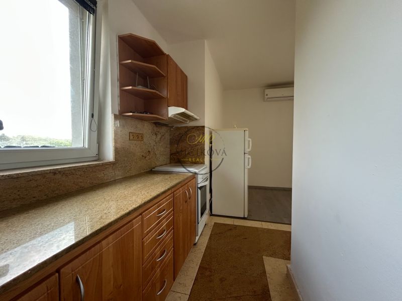 Küche in einer 2-Zimmer-Wohnung mit Arbeitsplatte aus Stein und Fenster.