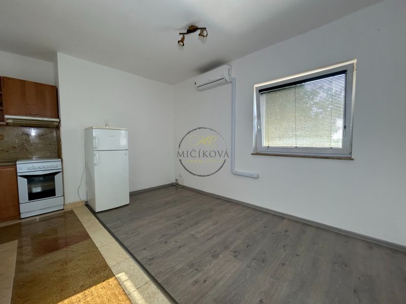 Küche in einer 2-Zimmer-Wohnung mit Holzboden, weißem Kühlschrank und Herd.