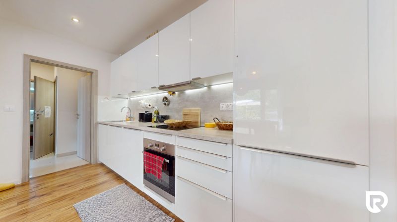 Küche mit Geräten, weißen Schränken und Holzboden in einer 3-Zimmer-Wohnung.