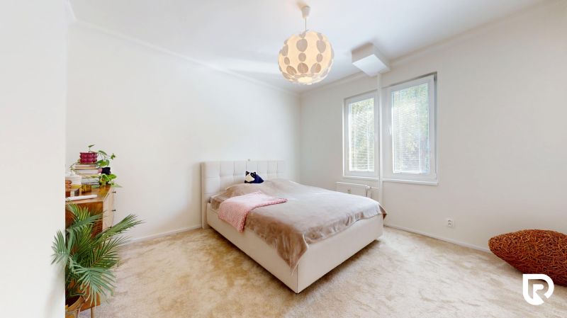 Helles Schlafzimmer mit Bett, Teppichboden und Fenster in einer 3-Zimmer-Wohnung.