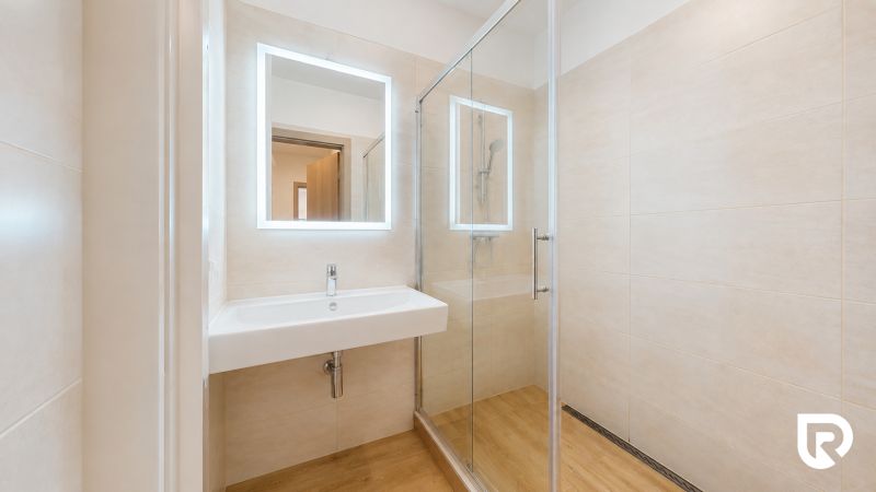Badezimmer in einer 3-Zimmer-Wohnung mit Waschbecken und Duschkabine, Boden mit Holzdekor.