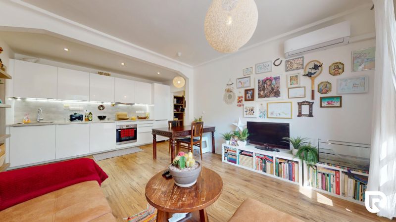 Wohnzimmer einer 3-Zimmer-Wohnung mit offener Küche und Boden in Holzoptik.