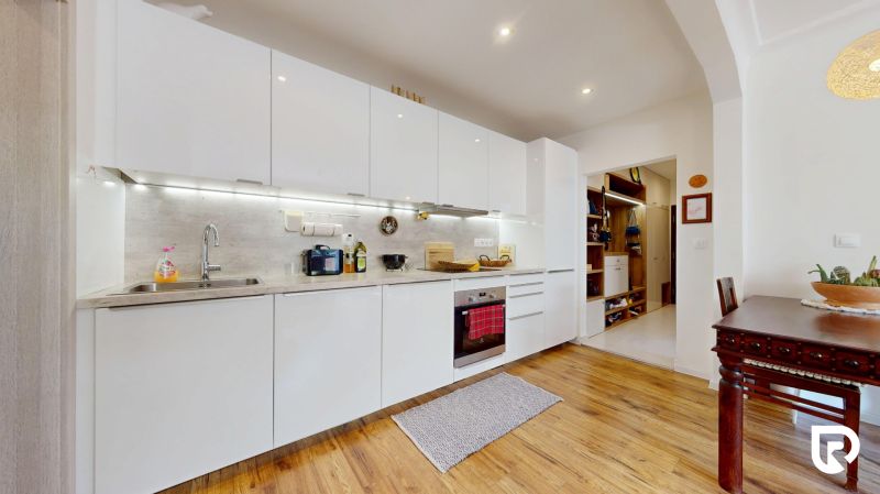 Küche in einer 3-Zimmer-Wohnung mit weißer Küchenzeile und Holzboden.