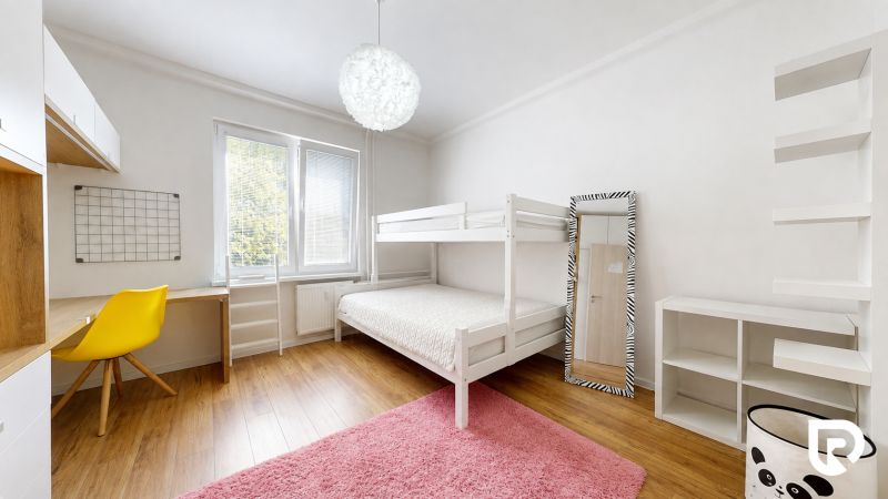 Kinderzimmer in einer 3-Zimmer-Wohnung mit Etagenbett, gelbem Stuhl, Regalen und Boden in Holzoptik.