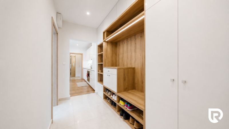 Flur mit Schuhschrank und Kleiderschrank in einer 3-Zimmer-Wohnung, Holzdekor und weiße Elemente.