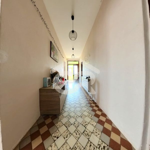 Der Flur eines Einfamilienhauses mit gefliestem Boden, einer Kommode und Lampen an der Decke.