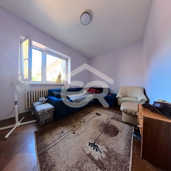Wohnzimmer in einem Einfamilienhaus mit einem blauen Sofa, einem Sessel und einem Teppich auf einem Boden mit Holzdekor.