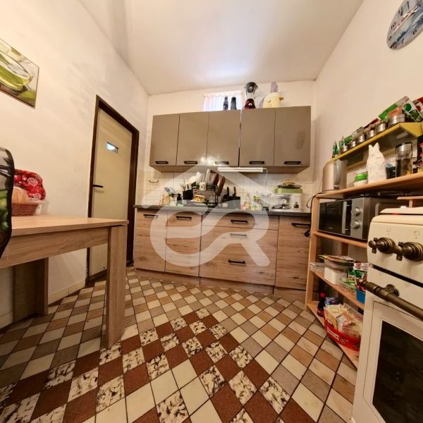 Küche in einem Einfamilienhaus mit Fliesen und Möbeln in Holzdekor.
