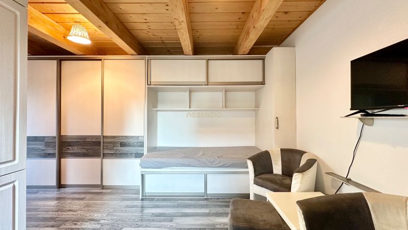 Wohnbereich in einer 2-Zimmer-Wohnung mit Fernseher, Sofa und eingebautem Bett.