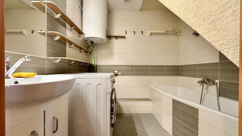 Badezimmer in einer 2-Zimmer-Wohnung mit Badewanne, Waschbecken, Waschmaschine und Boiler.