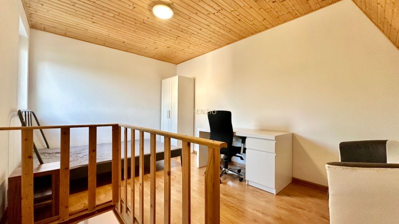 Helles Zimmer in einer 2-Zimmer-Wohnung mit Holzelementen und Schreibtisch.