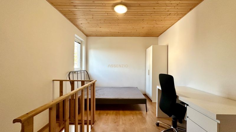 Schlafzimmer in einer 2-Zimmer-Wohnung mit Holzboden, Holzdecke und Möbeln.