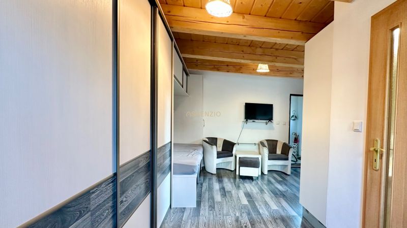 Wohnzimmer in einer 2-Zimmer-Wohnung mit Holzdecke und Boden in Holzoptik.