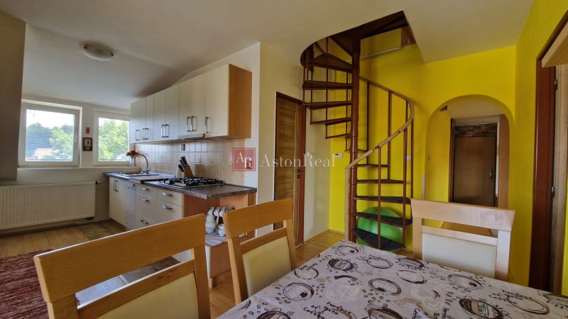 Küche in einer 2-Zimmer-Wohnung mit Wendeltreppe und hellen Schränken.