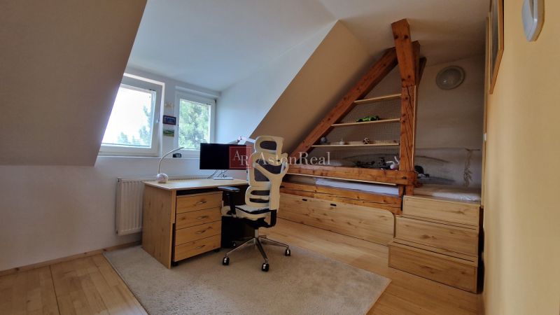 Dachbodenkantoor mit Schreibtisch, Stuhl und Holzboden in einer 2-Zimmer-Wohnung.