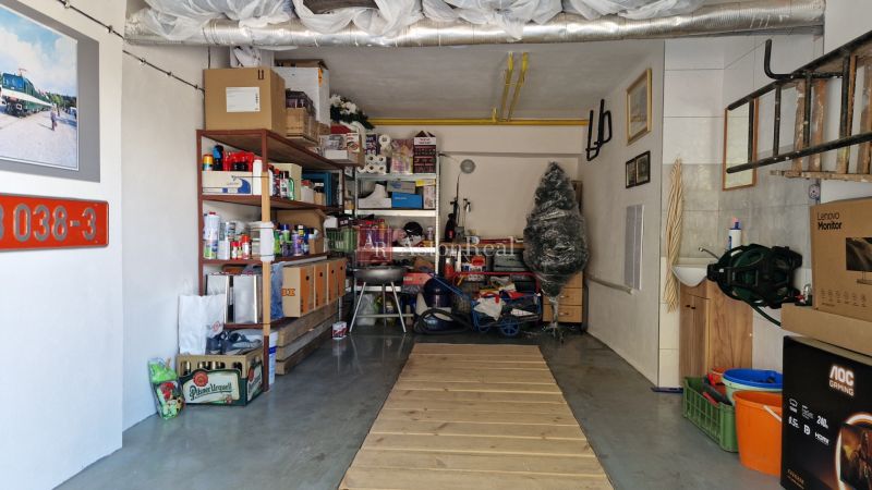 Eine Garage voller gelagerter Gegenstände und Regalsysteme, neben einem Waschbecken und einer Leiter.