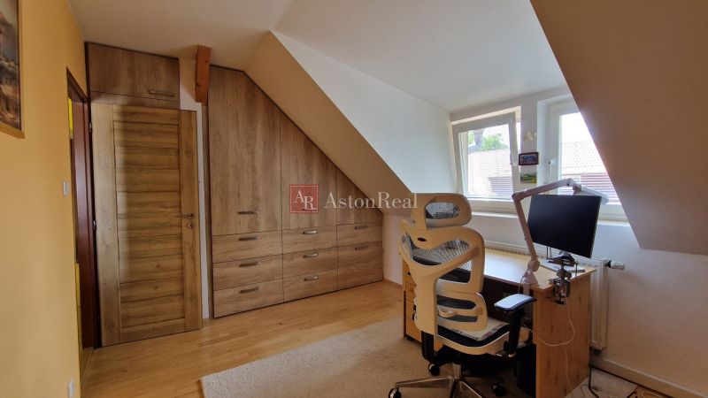 Dachboden mit Holzelementen, Schreibtisch und Stuhl in einer 2-Zimmer-Wohnung.