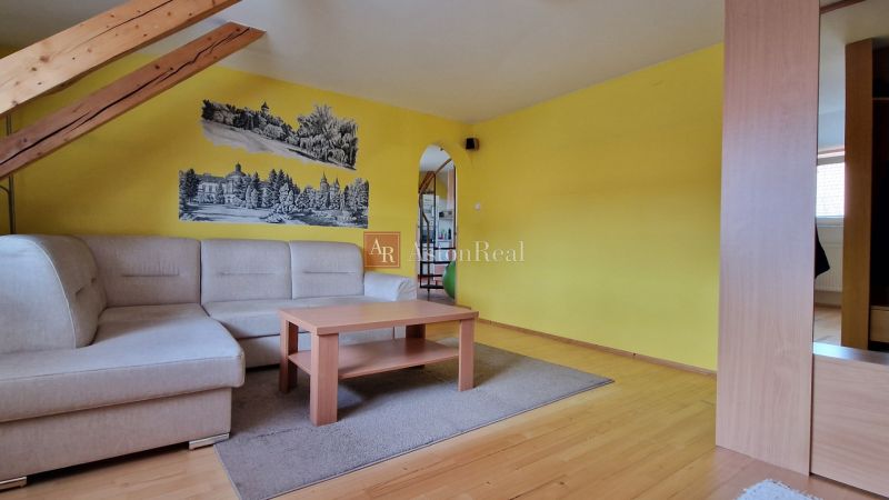 Wohnzimmer mit Sofa, Holzboden und gelben Wänden in einer 2-Zimmer-Wohnung.