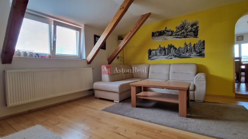 Wohnzimmer mit Sofa, Tisch und Boden in Holzoptik in einer 2-Zimmer-Wohnung.