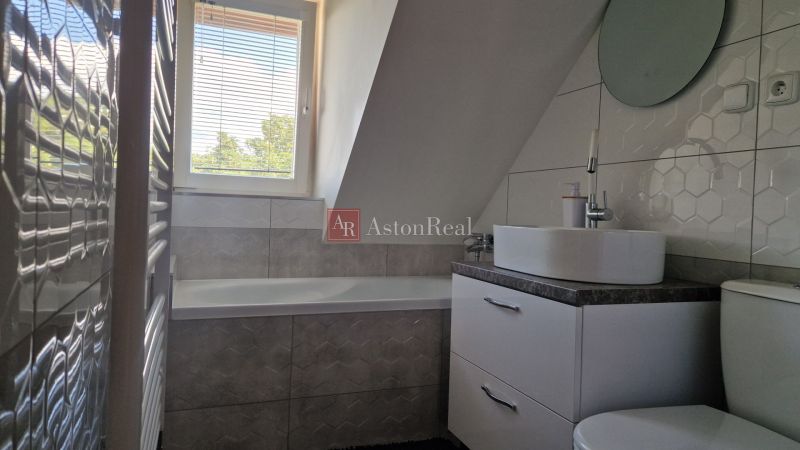 Badezimmer in einer 2-Zimmer-Wohnung mit Badewanne, Waschbecken und sechseckigen Fliesen.
