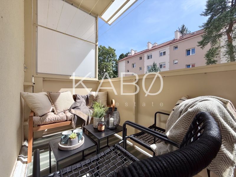 Balkon einer 2-Zimmer-Wohnung mit gemütlicher Sitzecke und Grünpflanzen.