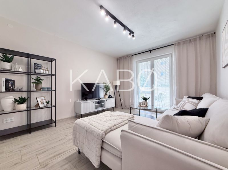 Helles Wohnzimmer in einer 2-Zimmer-Wohnung mit Regal und Sofa, Boden mit Holzdekor.