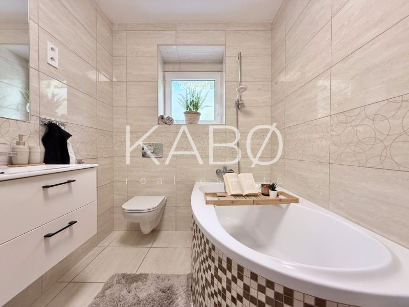 Elegantes Badezimmer in einer 2-Zimmer-Wohnung mit Badewanne, Waschbecken und Toilette.