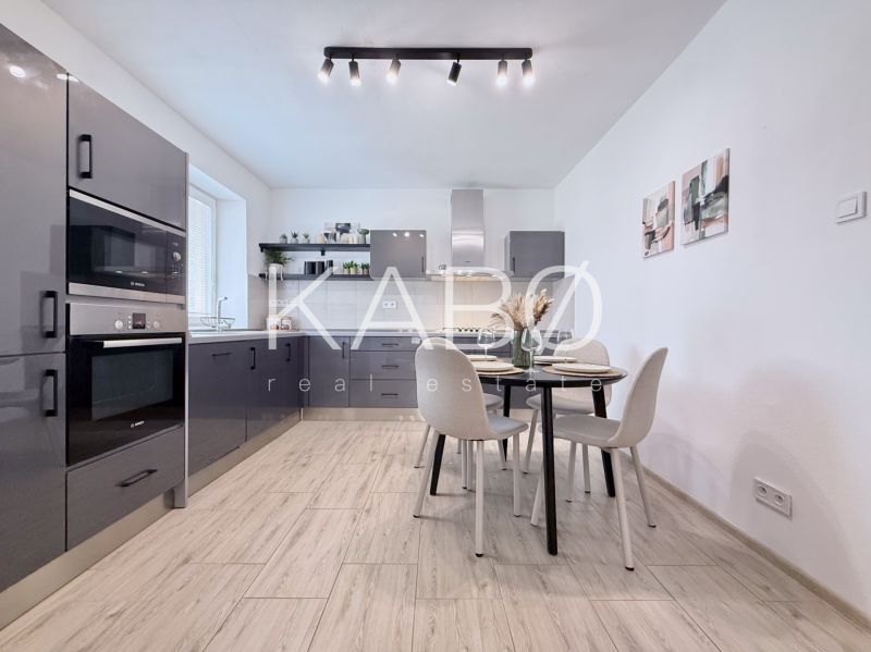 Moderne Küche in einer 2-Zimmer-Wohnung mit Holzboden und Esstisch.
