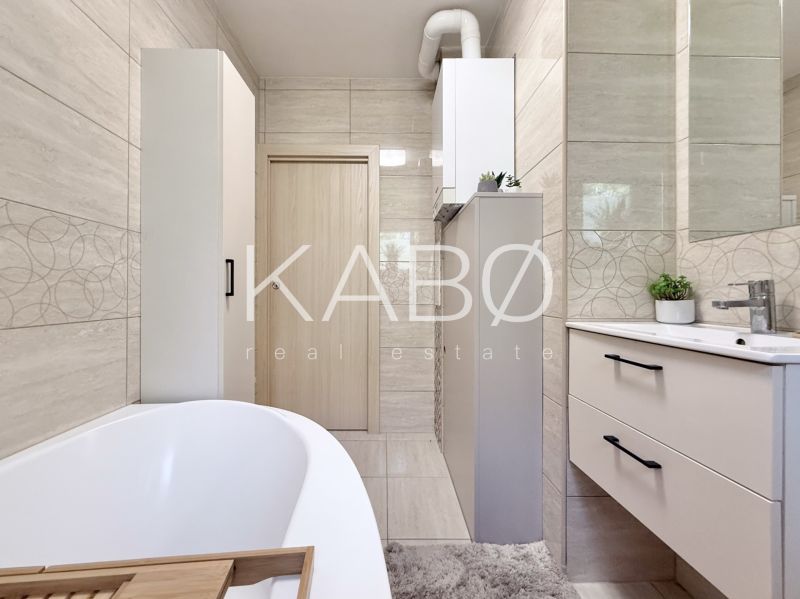 Badezimmer in einer 2-Zimmer-Wohnung mit Badewanne, Möbeln und Fliesen mit geometrischen Mustern dekoriert.