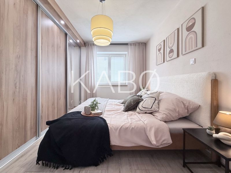 Schlafzimmer in einer 2-Zimmer-Wohnung mit Holzboden, großem Einbauschrank und Wanddekorationen.