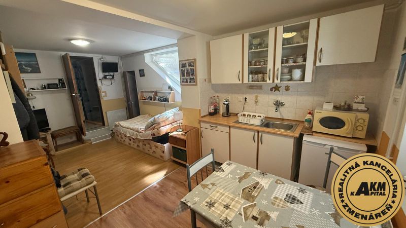 Küchenecke mit Schränken, Tisch und Sofa, Boden mit Holzdekor in einem Einfamilienhaus.