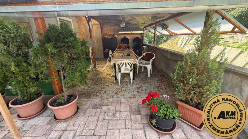 Die Terrasse eines Einfamilienhauses in Zvolen mit Holzdekor, einem Tisch und Pflanzen in Töpfen.