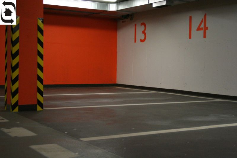 Parkplätze und eine orangefarbene Wand in der Garage mit gelben und schwarzen Säulen.