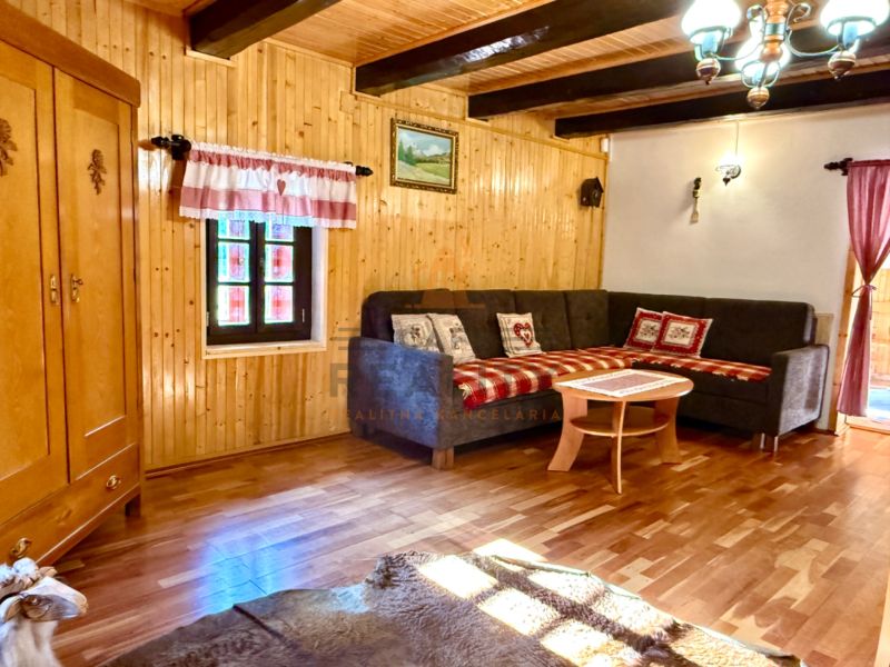 Innenraum eines Einfamilienhauses mit Ecksofa, Schrank und Bodenbelag in Holzoptik.