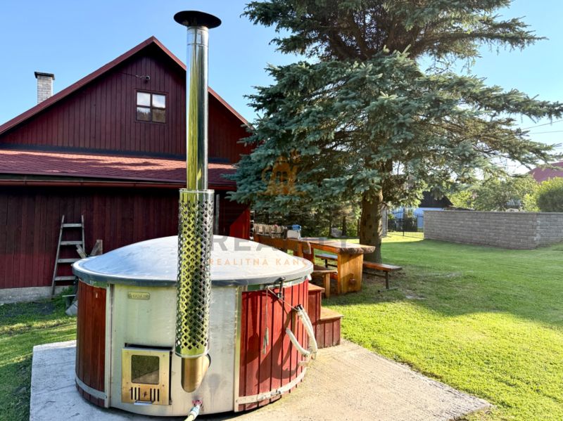 Ein Einfamilienhaus in der Jána Švermu Straße in Šumiac mit einem Whirlpool und einem Holztisch im Garten.