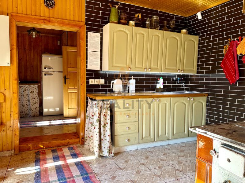 Küche in einem Einfamilienhaus mit einem Retro-Kühlschrank, Küchenzeile und schwarzen Fliesen.