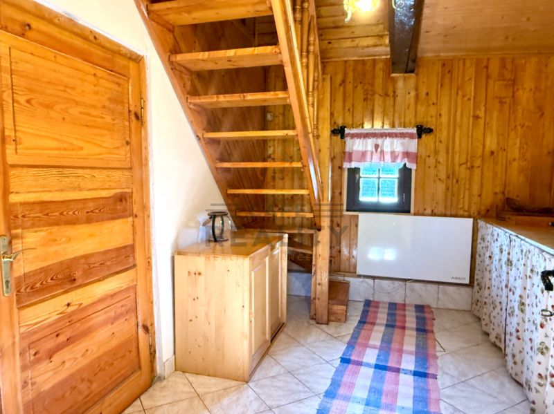 Innenraum eines Einfamilienhauses mit Holztreppe, -decke und -türen, Fliesen auf dem Boden.