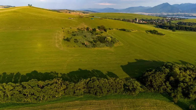 Grüne Wiesen und Bäume mit Blick auf das Dorf in Liptovský Trnovec, besondere Immobilien.