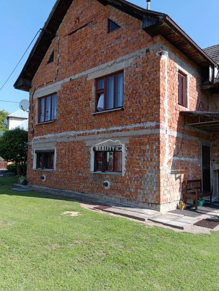 Ein Einfamilienhaus in Ovčiarsko mit einer unverputzten Ziegelfassade und einem grünen Rasen für Grundstücke - Wohnen.